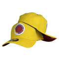 Gorra Colombia Amarilla con Escudo en Relieve y Visera Vinotinto.